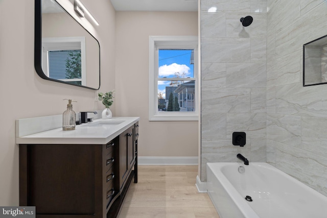 bathroom featuring hardwood / wood-style flooring, vanity, and tiled shower / bath