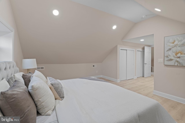 bedroom featuring light hardwood / wood-style floors, lofted ceiling, and a closet