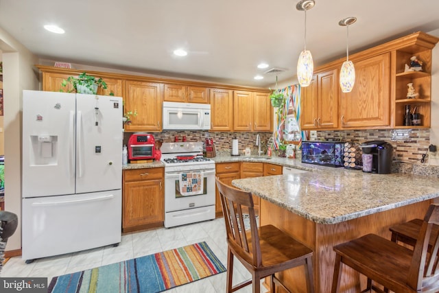 kitchen with kitchen peninsula, white appliances, decorative light fixtures, and a breakfast bar