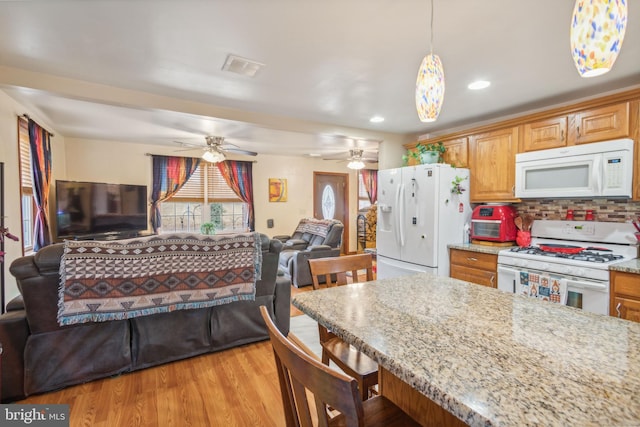 kitchen with light stone counters, pendant lighting, white appliances, decorative backsplash, and light wood-type flooring