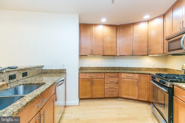 kitchen with sink, light hardwood / wood-style flooring, light stone countertops, and appliances with stainless steel finishes