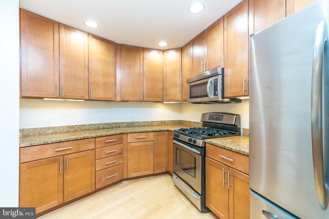 kitchen featuring light stone counters, light hardwood / wood-style flooring, and stainless steel appliances