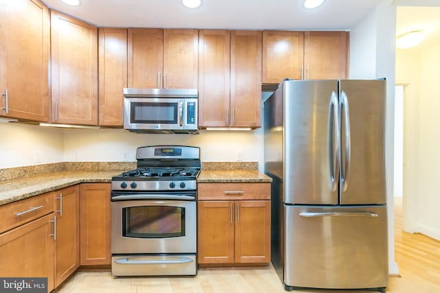 kitchen with light stone counters, stainless steel appliances, and light hardwood / wood-style floors