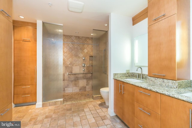 bathroom featuring tile patterned flooring, vanity, toilet, and a tile shower