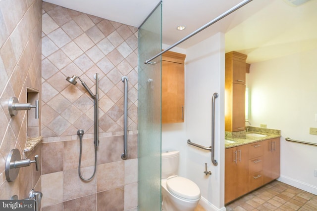 bathroom featuring a tile shower, tile patterned floors, vanity, and toilet