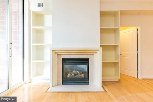 unfurnished living room with hardwood / wood-style floors and built in shelves