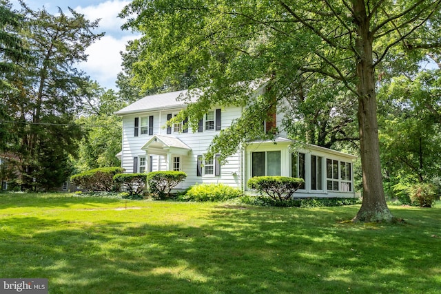 colonial home featuring a sunroom and a front yard