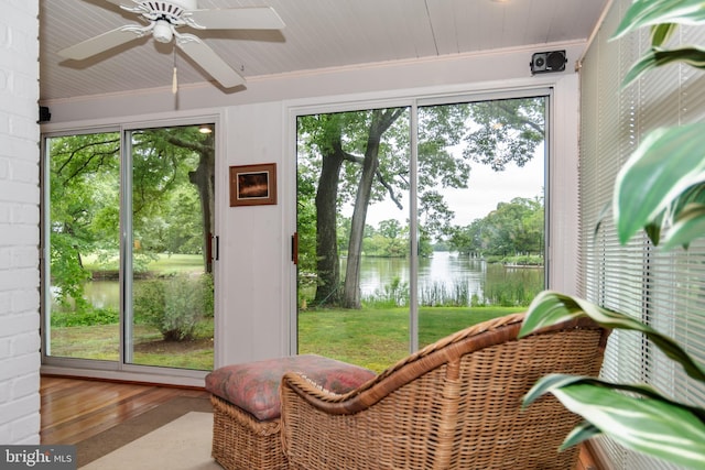 sunroom / solarium featuring a water view and ceiling fan