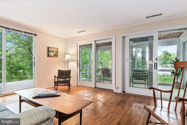 living area with hardwood / wood-style floors, plenty of natural light, and visible vents