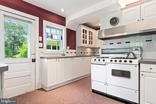 kitchen featuring range with two ovens, decorative backsplash, glass insert cabinets, white cabinets, and exhaust hood