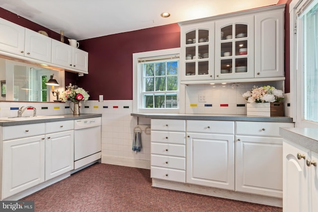 kitchen with tile walls, glass insert cabinets, white cabinets, a sink, and dishwasher