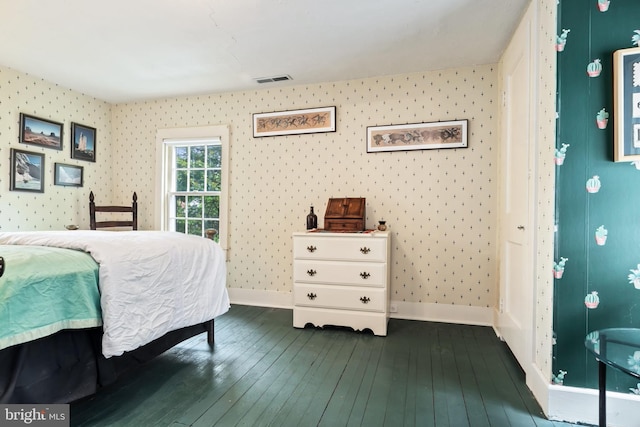 bedroom featuring wallpapered walls, visible vents, baseboards, and dark wood finished floors