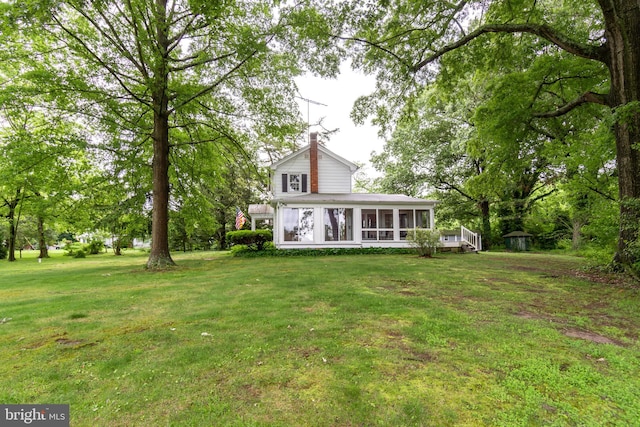 rear view of property with a yard and a sunroom