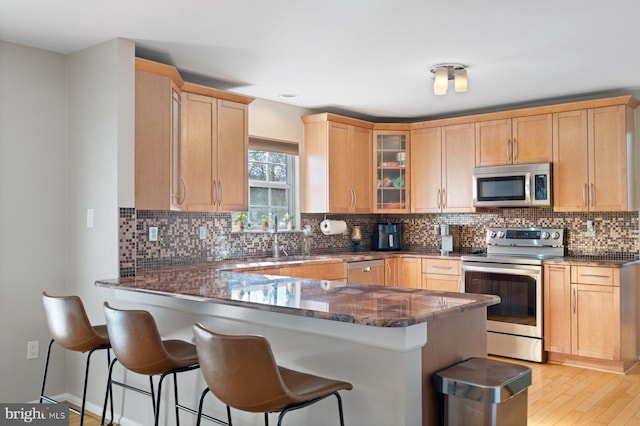 kitchen with appliances with stainless steel finishes, sink, kitchen peninsula, and dark stone counters