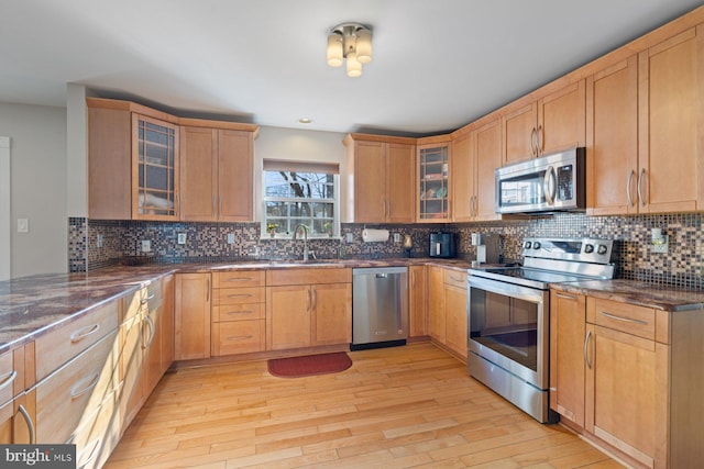 kitchen featuring stainless steel appliances, tasteful backsplash, sink, and light hardwood / wood-style flooring