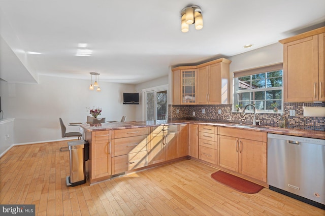 kitchen featuring pendant lighting, sink, light hardwood / wood-style floors, stainless steel dishwasher, and kitchen peninsula