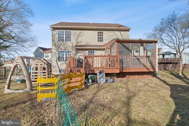 rear view of property featuring a wooden deck, a yard, a playground, and a sunroom