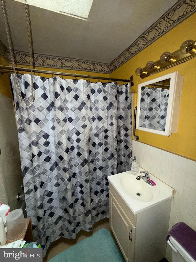 bathroom featuring walk in shower, vanity, tile walls, and toilet