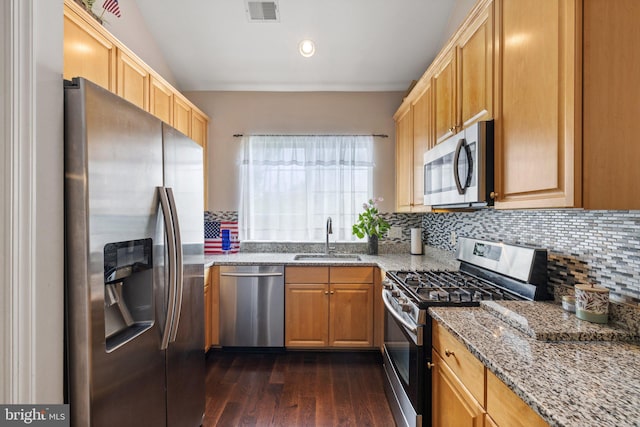 kitchen featuring tasteful backsplash, visible vents, light stone countertops, stainless steel appliances, and a sink