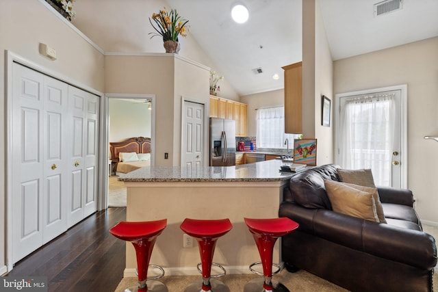 kitchen featuring visible vents, light stone counters, stainless steel appliances, lofted ceiling, and dark wood-style flooring