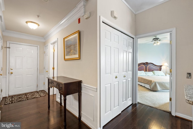 entryway with a wainscoted wall, dark wood-type flooring, crown molding, and a decorative wall