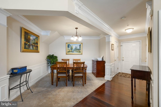 dining room featuring a notable chandelier, ornamental molding, wainscoting, and a decorative wall