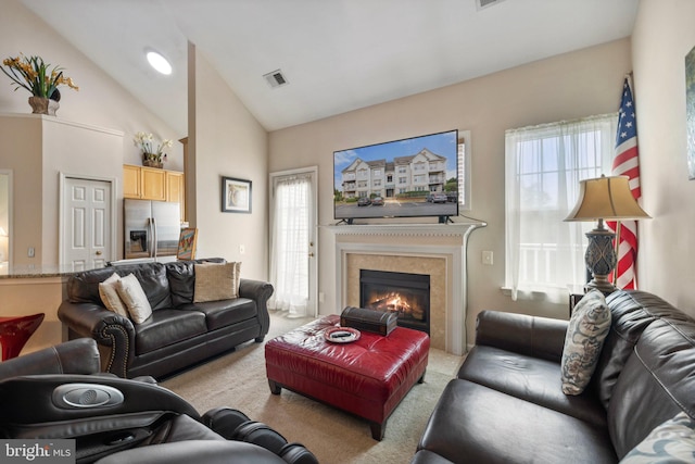 living area featuring visible vents, high vaulted ceiling, a glass covered fireplace, and carpet flooring