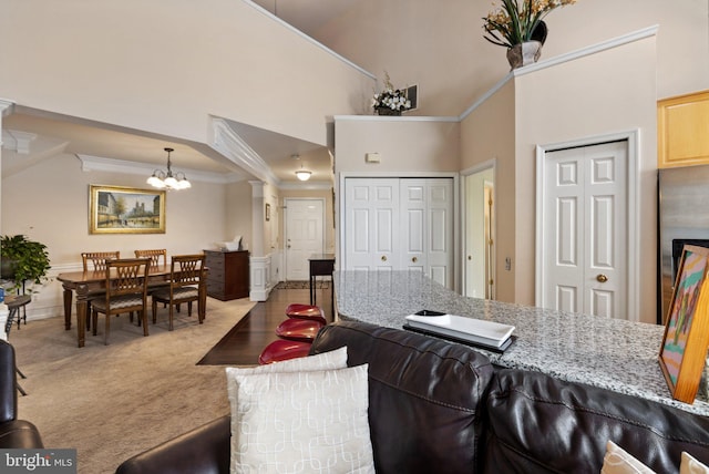 living room featuring light colored carpet, a high ceiling, crown molding, and an inviting chandelier