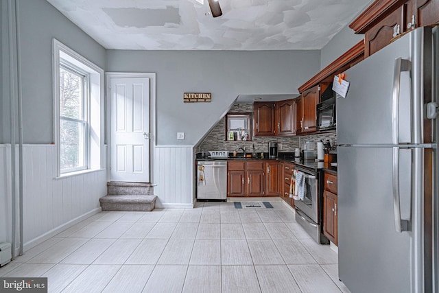 kitchen featuring backsplash, wooden walls, ceiling fan, light tile patterned floors, and stainless steel appliances