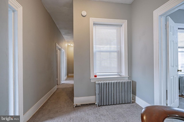 hallway featuring radiator heating unit and light colored carpet