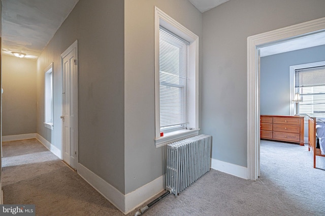 hallway featuring radiator heating unit and light colored carpet