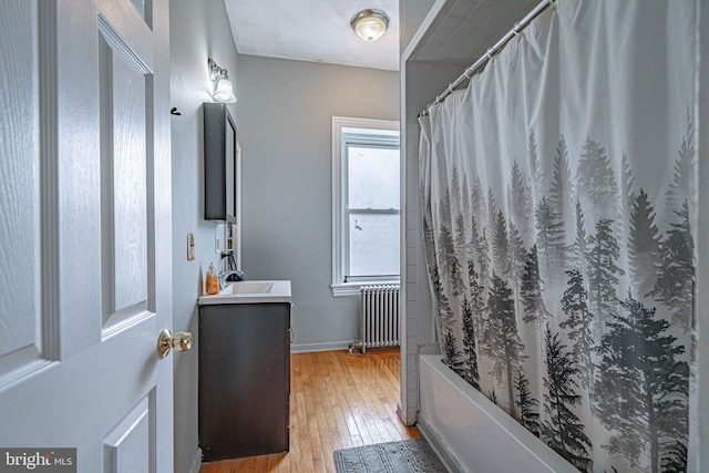 bathroom with radiator heating unit, vanity, wood-type flooring, and shower / tub combo