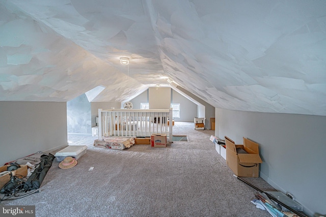 unfurnished bedroom featuring carpet, vaulted ceiling, and a crib