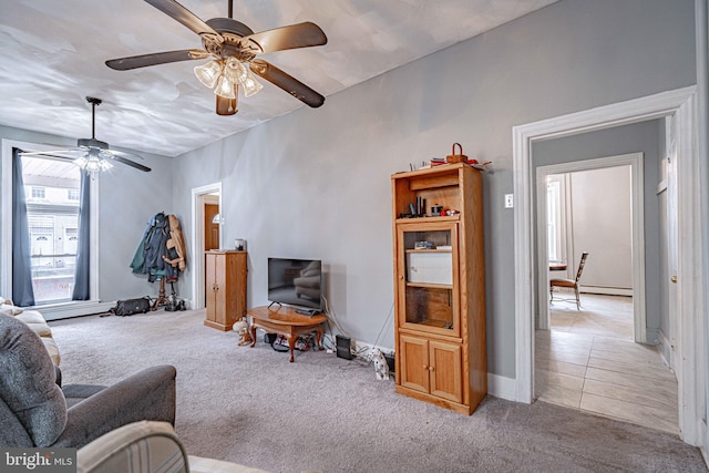 living room with baseboard heating, light carpet, and ceiling fan