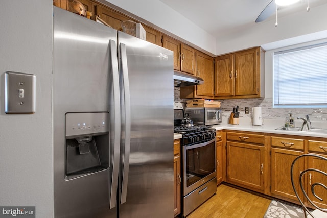 kitchen with ceiling fan, sink, light hardwood / wood-style floors, decorative backsplash, and appliances with stainless steel finishes