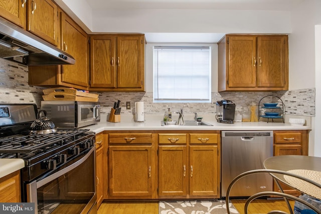 kitchen with tasteful backsplash, light hardwood / wood-style flooring, exhaust hood, and appliances with stainless steel finishes