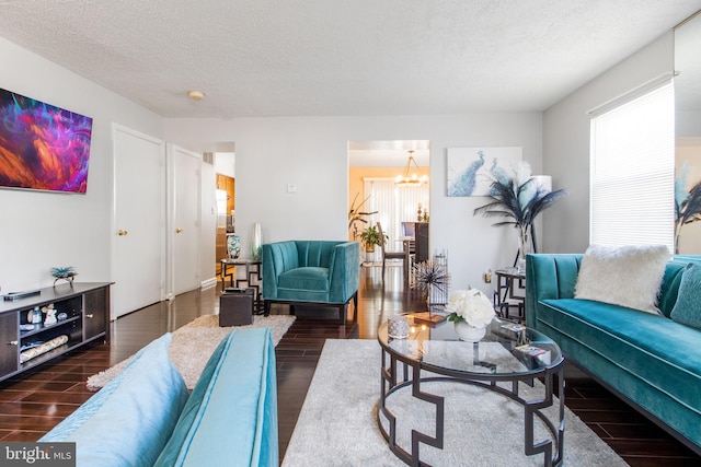 living room featuring a notable chandelier, dark hardwood / wood-style flooring, and a textured ceiling