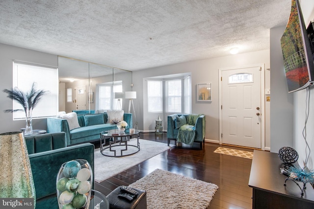 living room with a textured ceiling, a healthy amount of sunlight, and dark wood-type flooring