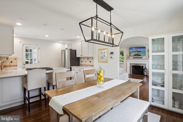 dining area featuring dark hardwood / wood-style floors, sink, a high end fireplace, and an inviting chandelier