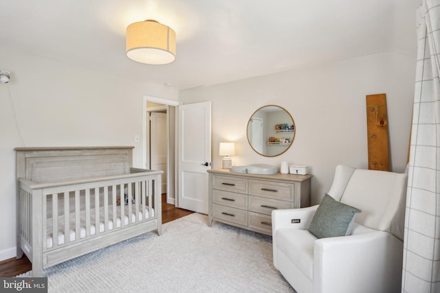 bedroom with light wood-type flooring and a nursery area