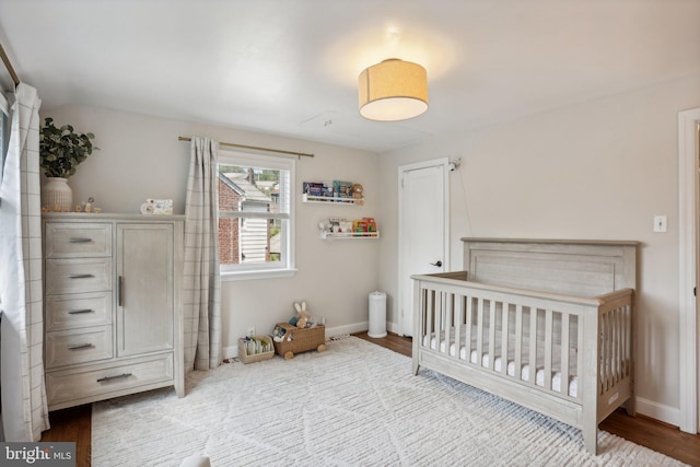 bedroom with hardwood / wood-style floors and a crib