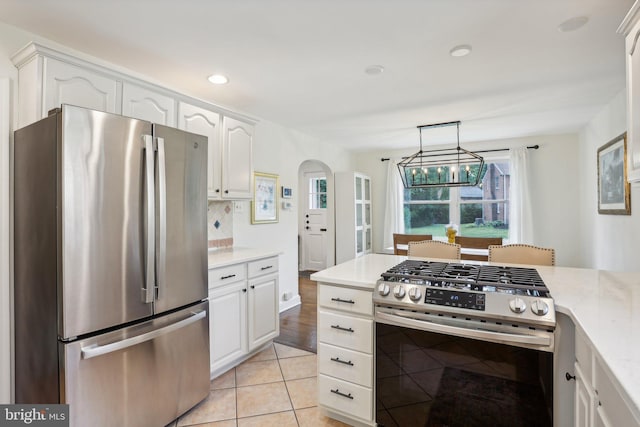 kitchen featuring white cabinets, pendant lighting, decorative backsplash, light tile patterned flooring, and appliances with stainless steel finishes