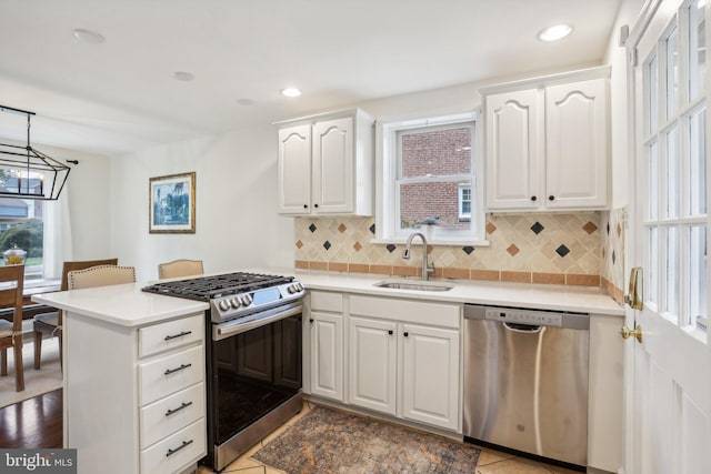 kitchen featuring pendant lighting, white cabinets, sink, kitchen peninsula, and stainless steel appliances