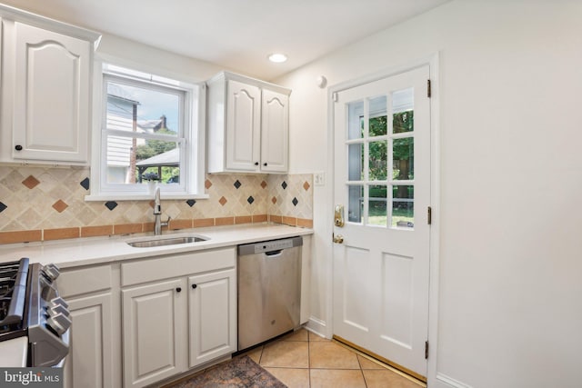 kitchen with sink, light tile patterned floors, backsplash, white cabinets, and appliances with stainless steel finishes