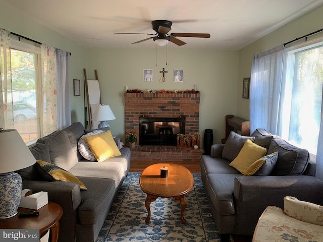 living room with a brick fireplace, ceiling fan, dark hardwood / wood-style flooring, and plenty of natural light