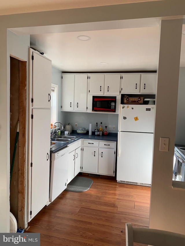 kitchen featuring white appliances, white cabinetry, dark hardwood / wood-style floors, and sink