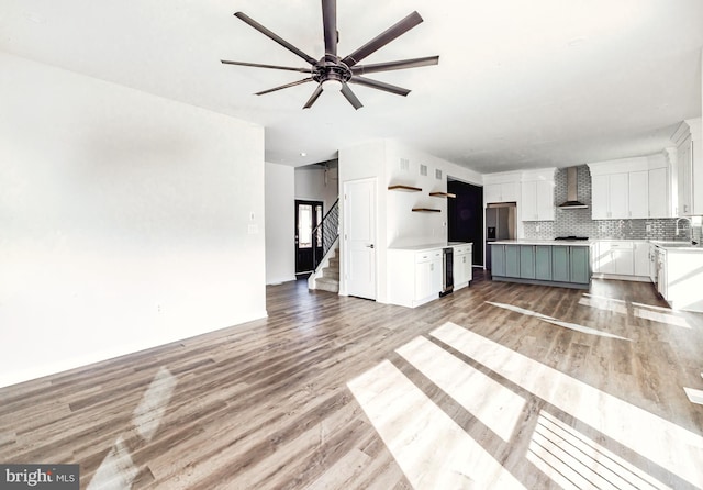 unfurnished living room featuring ceiling fan, sink, and light hardwood / wood-style floors