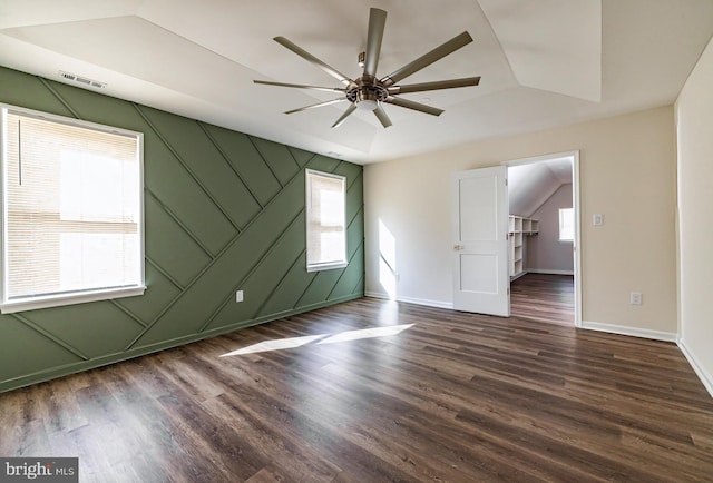 empty room with ceiling fan, a healthy amount of sunlight, lofted ceiling, and dark wood-type flooring