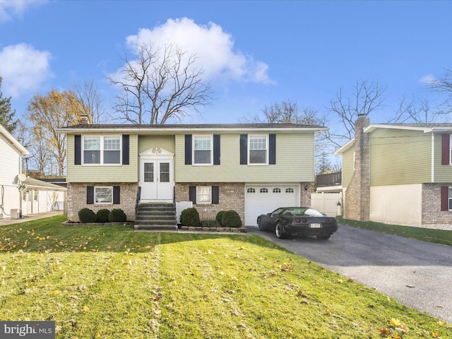 raised ranch with a garage, a front lawn, and cooling unit