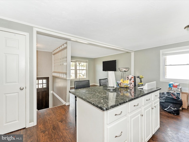 kitchen featuring a kitchen island, dark stone counters, white cabinetry, and dark wood-type flooring